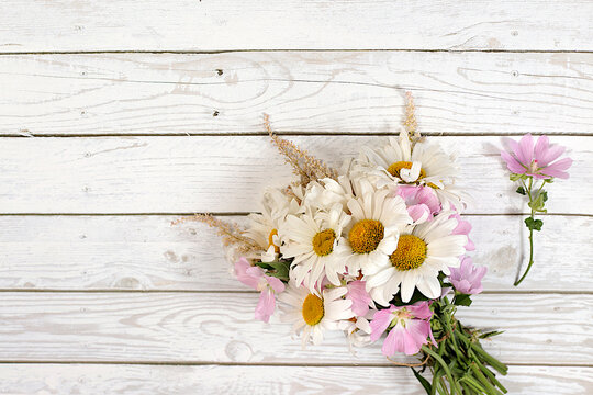 Bouquet of white daisies and mallow on wooden background, summer and autumn product advertising banner, abstract floral arrangement, flat lay still life, autumn holiday card with space for text,