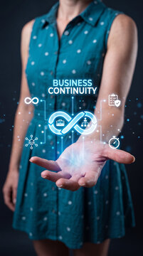 A woman holds out her hand with a glowing infographic representing business continuity, featuring an infinity loop symbol and various icons representing different business processes and data flow