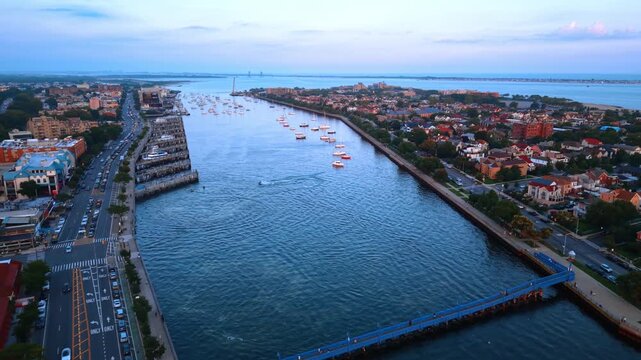 Flyover the Ocean Avenue Footbridge across the Sheepshead Bay at sunset time. Approaching the multiple boats on the waterscape.