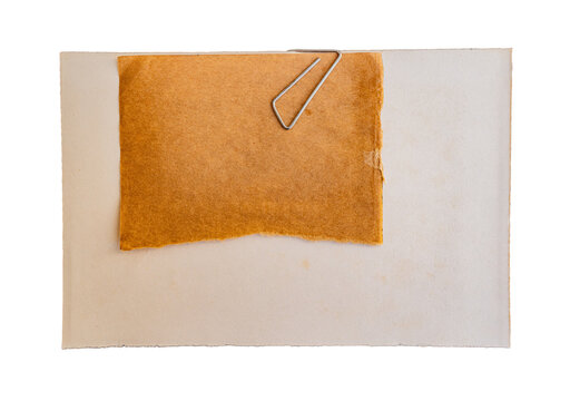 Hoja de papel naranja sujeta con clip met&aacute;lico sobre fondo beige, composici&oacute;n minimalista con espacio para texto