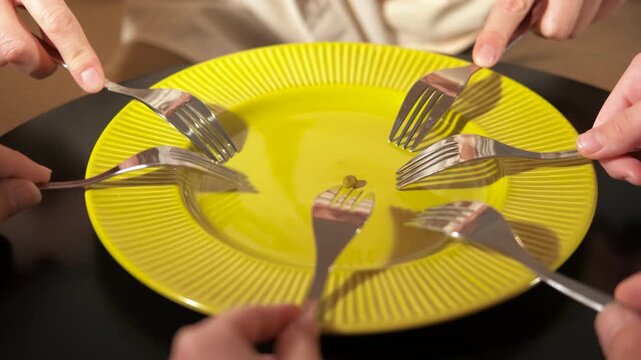 Many people fighting with forks for one pea. Numerous hands with forks reach for a single green pea on a yellow plate, symbolizing concepts like scarcity, competition for resources, social inequality