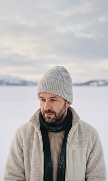 Close up portrait of bearded adult man wearing winter beanie hat fleece jacket and scarf outdoors
