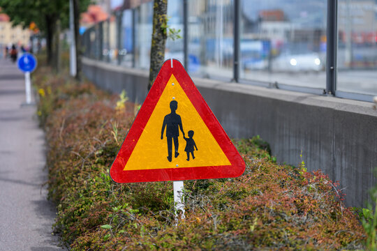 Swedish triangular pedestrian warning sign beside city walkway.