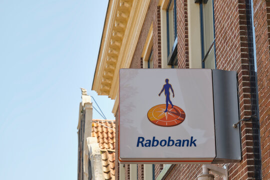 A close-up view of the Rabobank logo and name displayed on a white sign attached to a red brick building facade in The Netherlands