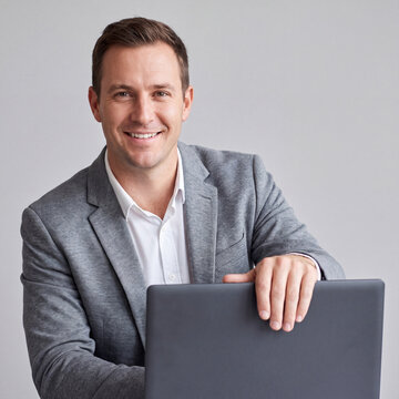 Smiling male consultant with closed laptop on gray studio background