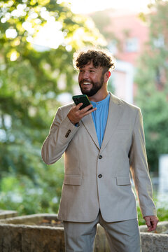 Businessman recording voice message on smartphone outdoors