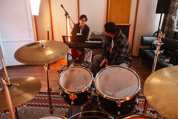 Fototapeta premium Two young musicians playing keyboard in a creative music studio