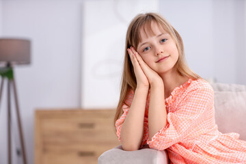 Fototapeta premium Portrait of cute little girl on sofa at home. Space for text