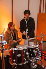 Fototapeta premium Two young musicians teaching drumming in a creative music studio