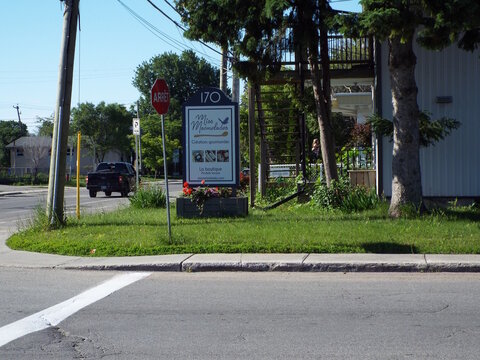 Gatineau, Quebec, Canada &ndash; June 21, 2026: A sign for "Miss Marmelades" stands near a street corner with an octagon stop sign and a moving pickup truck on Bd Greber.