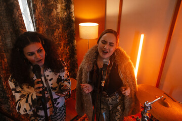 Fototapeta premium Two young musicians singing songs in a creative music studio
