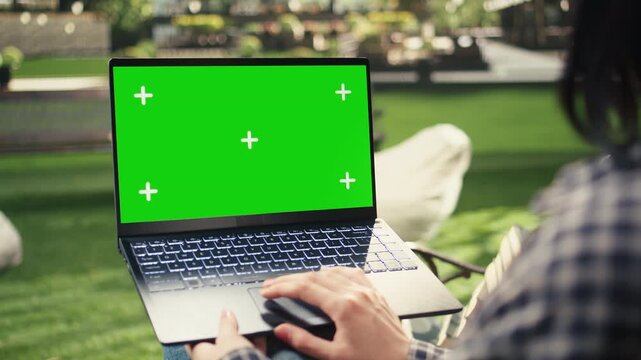 Green screen mockup sits on a bench beside a laptop as a student works outdoors on campus, with a blurred background for editable education content, student life and independent campus study.