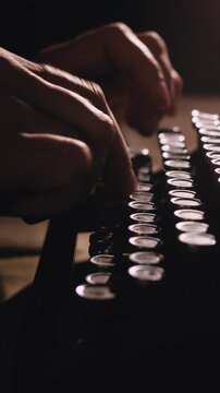 Hands typing on antique typewriter in the dark