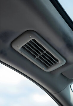 Automotive air conditioning vent on a gray ceiling panel inside a modern vehicle, climate control system, the functional design ensures optimal airflow for passenger comfort during travel