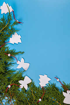 Christmas tree branches with white handmade decorations on blue background