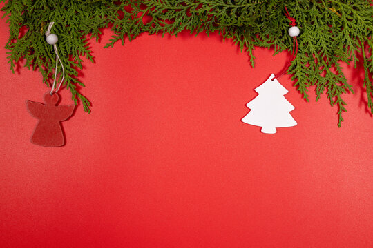 Christmas ornaments hanging from evergreen branches on red