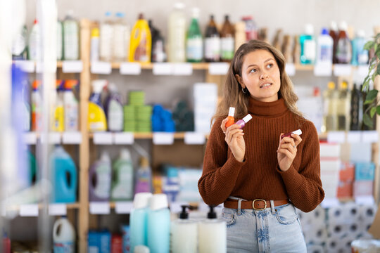 Selective young female customer choosing colorful nail polish in retail store