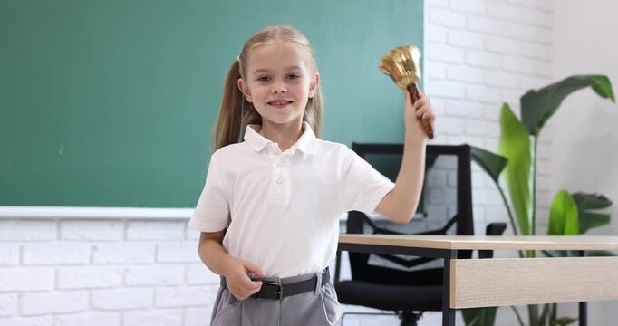 Little girl ringing school bell in classroom