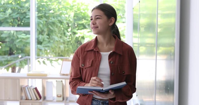 Teenage girl with book answering at chalkboard in classroom