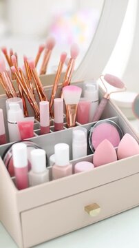 Organizer with different makeup products and brushes on vanity indoors. Camera moving left