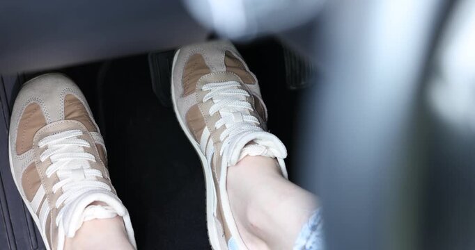 Woman pushing brake pedal in car, closeup on foot