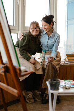 Two female artists smiling together in a colorful art studio