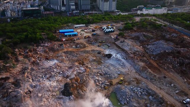 Reveal shot of rock blasting in massive construction site with parked heavy vehicles and construction waste dump at raidurgam, hyderabad, telangana, india. day time, push back shot, drone shot, 4k.