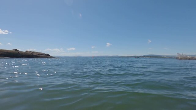 Low angle view of calm sea water floating past rocky skerry shore
