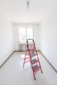 A red ladder in an empty room