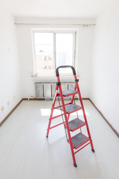 A red ladder in an empty room