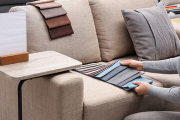 Woman with fabric samples on grey sofa in furniture store
