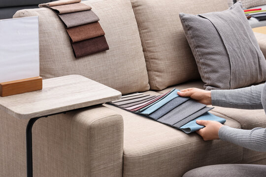 Woman with fabric samples on grey sofa in furniture store