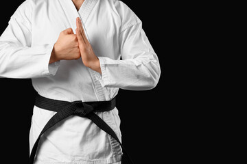 Fototapeta premium Young man practicing karate on black background