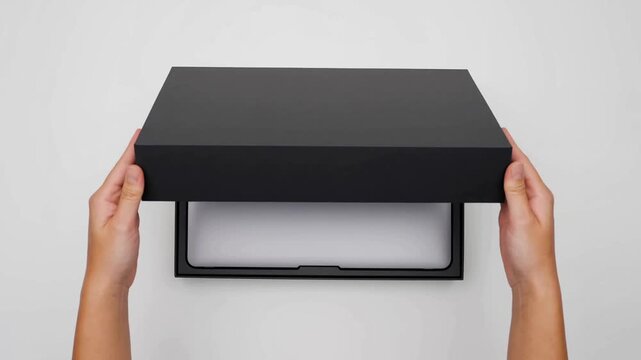 Top view closeup of hands opening luxury black box packaging on white background