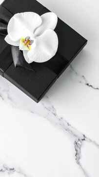 Gift box black gift white orchid marble background luxury present elegant wrapping minimal style wedding concept romantic surprise celebration mood Sleek black gift box with Christmas Concept
