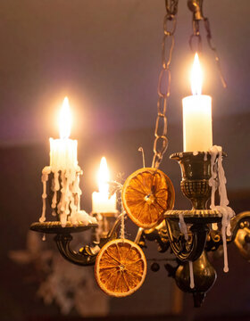 Vintage candlelight chandelier melting wax candle dried orange slice warm Christmas decor rustic holiday ambience cozy festive glow soft focus bokeh chain detail Christmas Concept