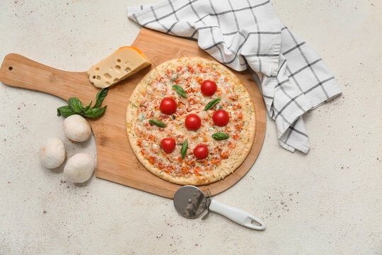 Tasty pizza, cutter and ingredients on light background