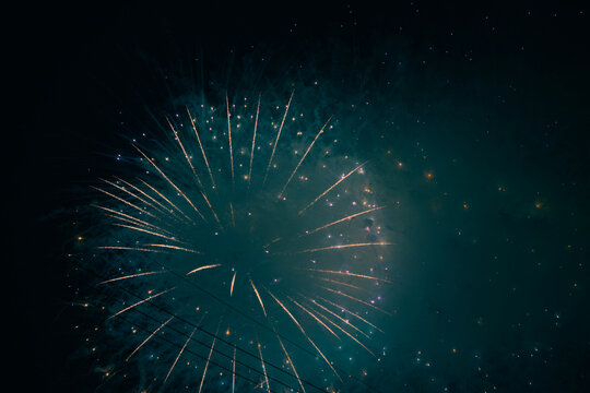 Large golden firework shell radiating through a smoky teal sky