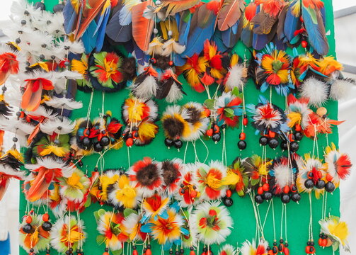 Traditional handmade earrings made from vibrant bird feathers and native Amazonian plant seeds by women from indigenous communities (Kichwa, Waorani, Shuar) in Ecuador.