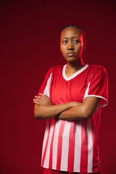 African American woman posing in studio with red backdrop, wearing striped jersey and stud earring