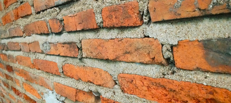 Close-up view of a rough red brick wall.