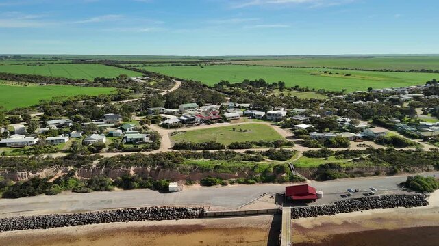 Port Julia, Yorke Peninsula, South Australia &ndash; 4K aerial drone view of jetty, sheltered beach, limestone cliffs, coastal township and Gulf St Vincent, beachfront holiday homes, surrounding farmland.
