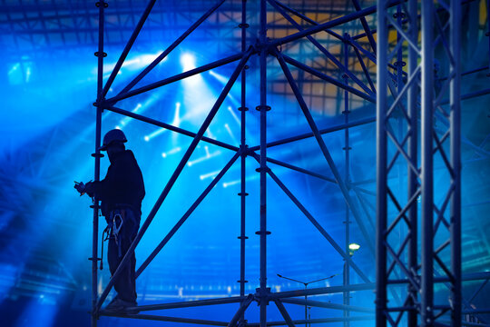 Stage construction. Rigging technician assembles concert truss structures and lighting support systems before a live event, ensuring safe installation and production setup.