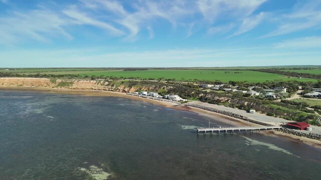 Port Julia, Yorke Peninsula, South Australia &ndash; 4K aerial drone view of jetty, sheltered beach, limestone cliffs, coastal township and Gulf St Vincent, beachfront holiday homes, surrounding farmland.