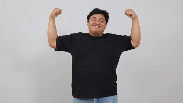 Smiling cheerful Asian overweight man showing biceps mucles on hands