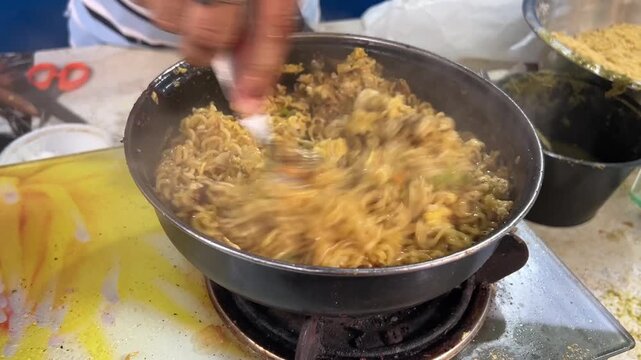 A mouth-watering close-up shot of special egg-fried Maggi noodles being freshly prepared with scrambled eggs and aromatic spices at a vibrant roadside food outlet, India.
