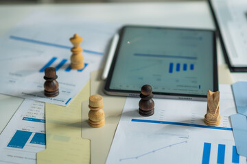 Close-up of chess pieces on financial graph reports and digital tablet for business strategy planning concept. © wanakit