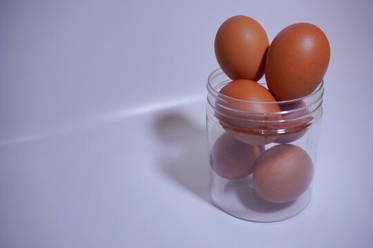 Chicken eggs in a clear jar, white background.