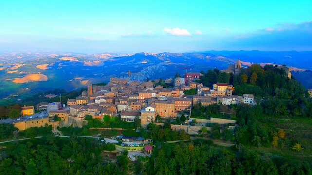SANTA VITTORIA IN MATENANO, ITALY - OCTOBER 10, 2025: Aerial push-in pedestal down shot of the town centre. Approaching the vintage buildings, church and belltower, construction sites, clock tower