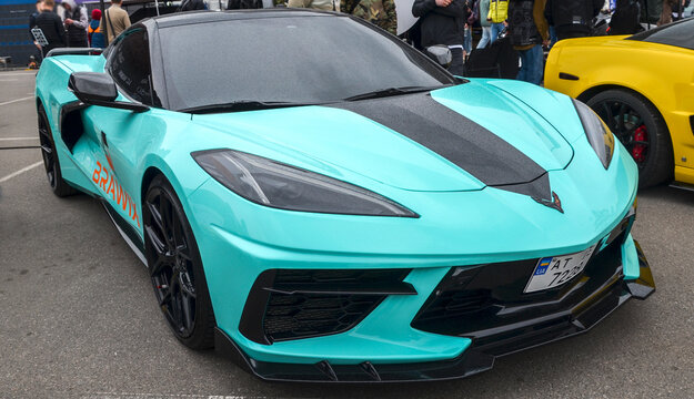 This mint green Chevrolet Corvette C8 represents a revolutionary shift to a mid-engine layout, boasting aggressive exotic styling, black racing stripes, and black wheels